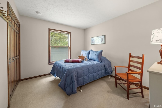 bedroom with light carpet, a textured ceiling, and baseboards