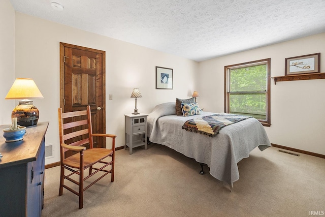 bedroom featuring light colored carpet, baseboards, and a textured ceiling