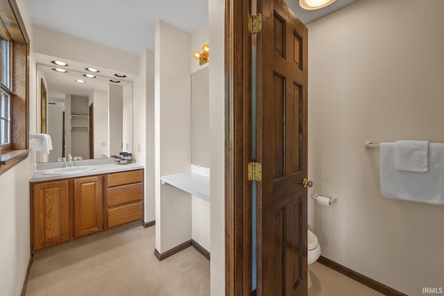 bathroom featuring baseboards, toilet, and vanity