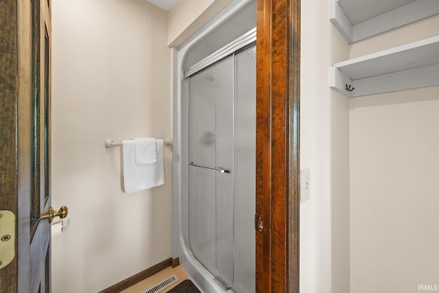 full bathroom featuring a shower stall and baseboards