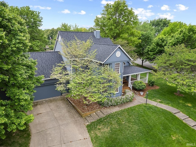 view of front facade featuring a shingled roof, a front lawn, a porch, concrete driveway, and an attached garage