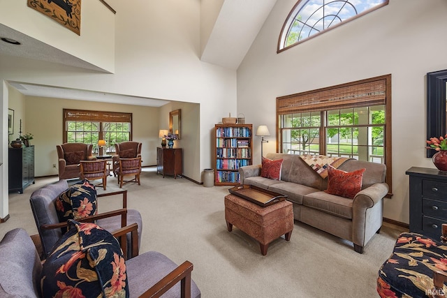 living room featuring light colored carpet, a high ceiling, and baseboards