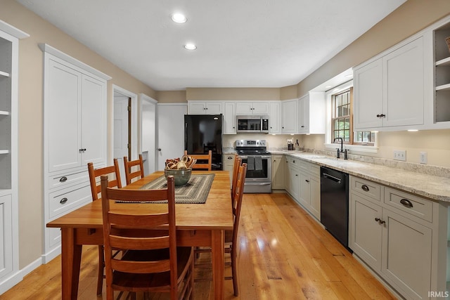 kitchen featuring black appliances, open shelves, a sink, light wood-type flooring, and white cabinetry