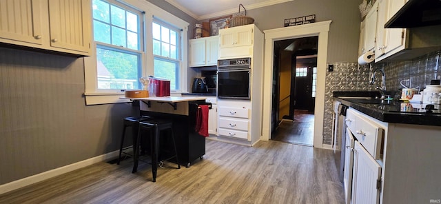 718 N Cherry St, Mount Carmel, IL 62439 - kitchen featuring black oven, under cabinet range hood, a sink, tasteful backsplash, and light wood-style floors