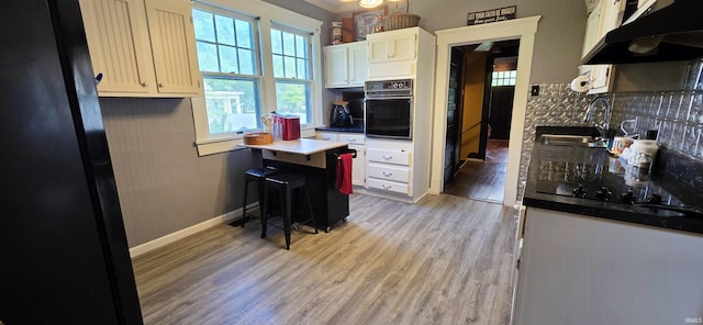 718 N Cherry St, Mount Carmel, IL 62439 - kitchen featuring black appliances, under cabinet range hood, a sink, light wood-type flooring, and backsplash