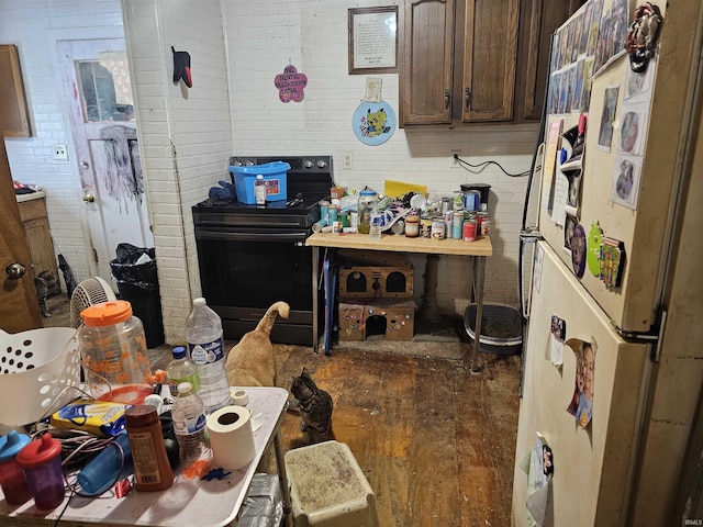 1211 N St, Logansport, IN 46947 - kitchen featuring freestanding refrigerator, black electric range oven, dark brown cabinetry, and brick wall