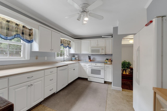 kitchen featuring white appliances, a sink, arched walkways, a ceiling fan, and light countertops
