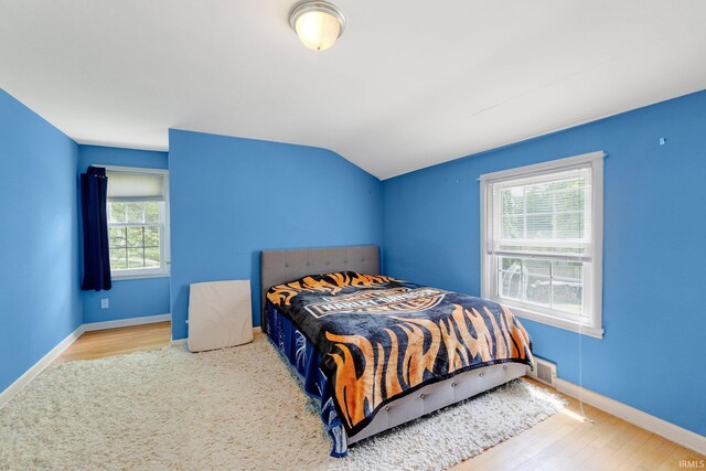 bedroom with wood finished floors, vaulted ceiling, and baseboards