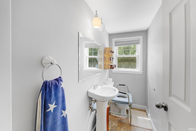 bathroom with baseboards, stone finish flooring, and toilet