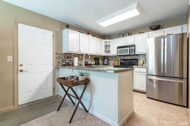 682 E Heather Dr, Bloomington, IN 47401 - kitchen featuring stainless steel appliances, tasteful backsplash, white cabinetry, and a peninsula