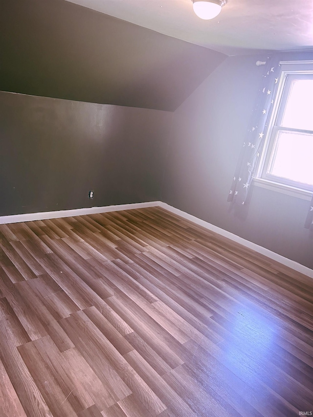 additional living space featuring vaulted ceiling, wood finished floors, and baseboards