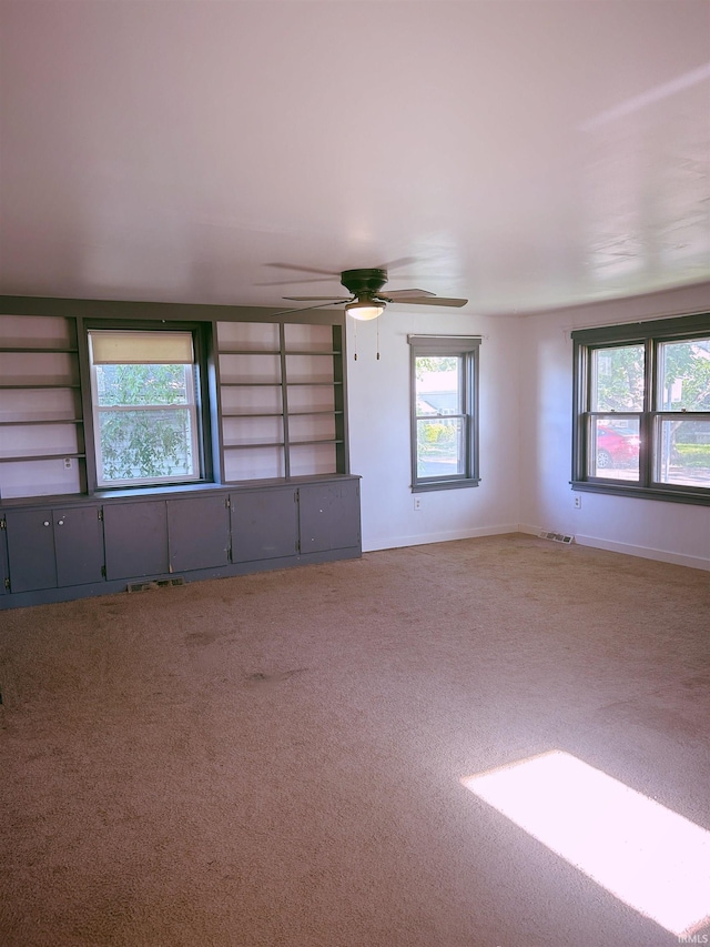 empty room featuring carpet floors, a ceiling fan, and baseboards