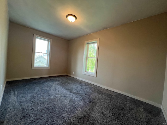 empty room featuring dark carpet and baseboards