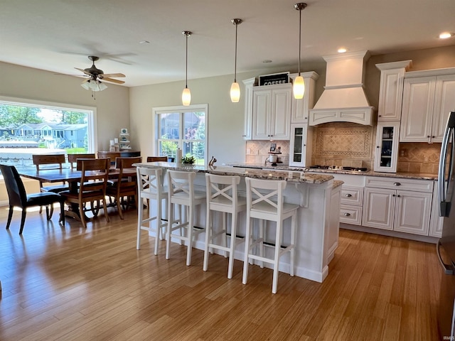 1620 Colonial Dr, Rochester, IN 46975 - kitchen with premium range hood, a ceiling fan, a breakfast bar, white cabinets, and gas cooktop