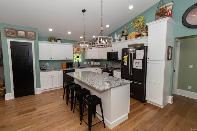 30512 Jaxon Dr, Elkhart, IN 46517 - kitchen with black appliances, a sink, a chandelier, a kitchen island, and white cabinetry