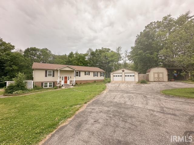 6330 Gardner Rd, Chandler, IN 47610 - split foyer home featuring an outdoor structure, a garage, a storage unit, a front yard, and view of wooded area