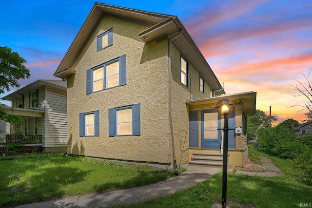 view of side of home featuring stucco siding, a lawn, and entry steps
