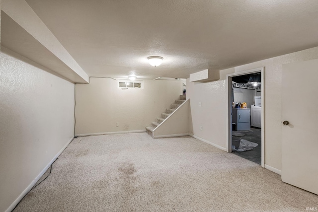 finished below grade area featuring washer / clothes dryer, carpet flooring, stairs, and a textured ceiling