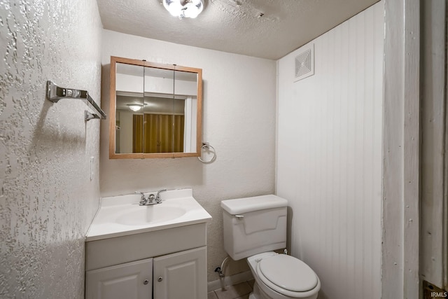 half bath featuring toilet, vanity, and tile patterned floors