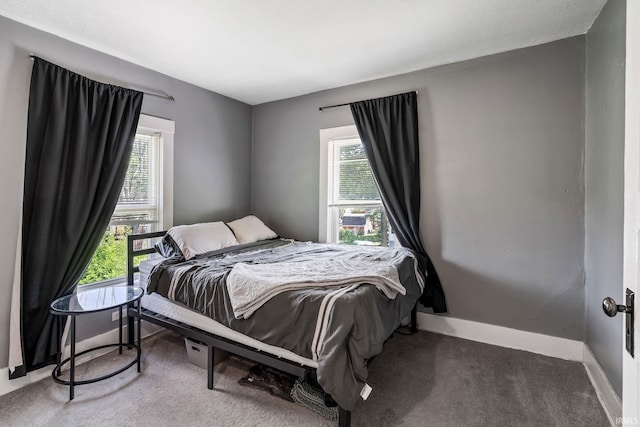 carpeted bedroom featuring multiple windows and baseboards