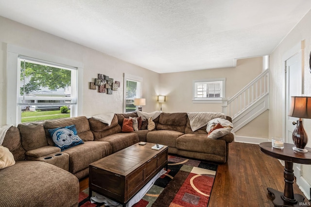 living area with hardwood / wood-style flooring, stairs, a textured ceiling, and baseboards