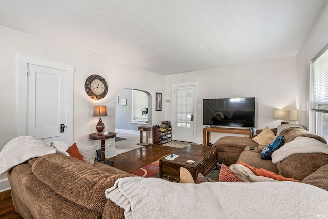 living room with wood finished floors, arched walkways, and baseboards