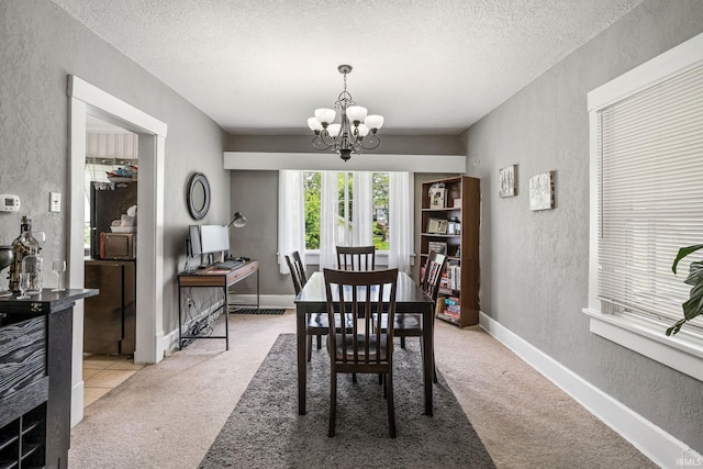 dining space featuring a textured wall, a chandelier, light carpet, and a textured ceiling