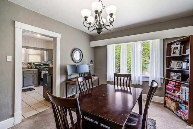 dining space with a chandelier, light tile patterned flooring, light colored carpet, a textured wall, and baseboards