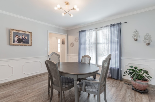7860 Cedar Ridge Dr, Evansville, IN 47715 - dining area with a wainscoted wall, a decorative wall, a chandelier, ornamental molding, and light wood finished floors