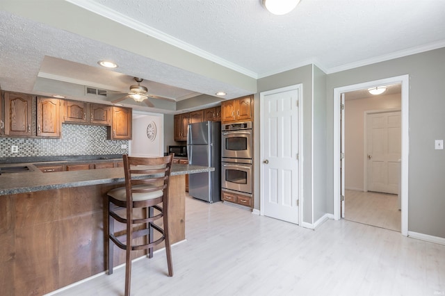 7860 Cedar Ridge Dr, Evansville, IN 47715 - kitchen with appliances with stainless steel finishes, a raised ceiling, light wood-style flooring, ornamental molding, and a textured ceiling