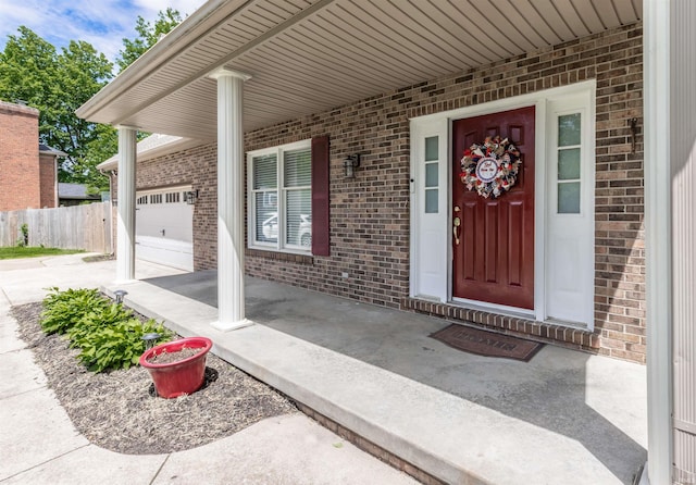 7860 Cedar Ridge Dr, Evansville, IN 47715 - view of exterior entry featuring brick siding, concrete driveway, an attached garage, and covered porch