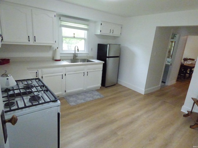 51044 Portage Rd, South Bend, IN 46628 - kitchen with freestanding refrigerator, white range with gas stovetop, a sink, white cabinetry, and baseboards