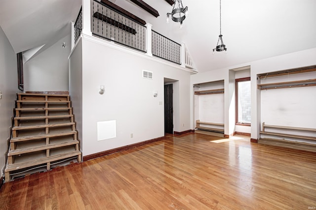 4302 Kessler Blvd N Drive, Indianapolis, IN 46220 - unfurnished living room featuring high vaulted ceiling, wood finished floors, baseboards, and stairs