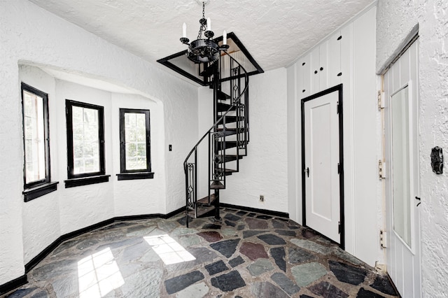 4302 Kessler Blvd N Drive, Indianapolis, IN 46220 - foyer with a chandelier, stone flooring, a textured wall, stairway, and a textured ceiling