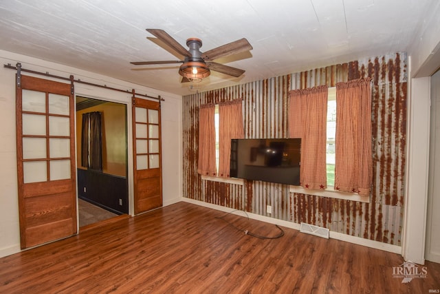 1809 E Royerton Rd, Muncie, IN 47303 - unfurnished living room with a barn door, wood finished floors, ceiling fan, and baseboards