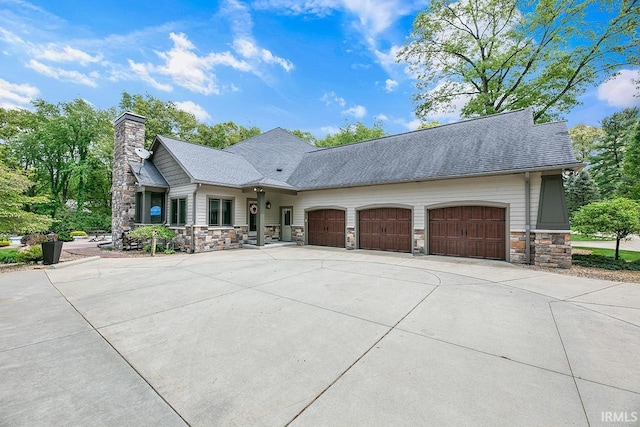 19861 County Road 16, Bristol, IN 46507 - view of front of home featuring stone siding, driveway, a garage, a chimney, and a shingled roof
