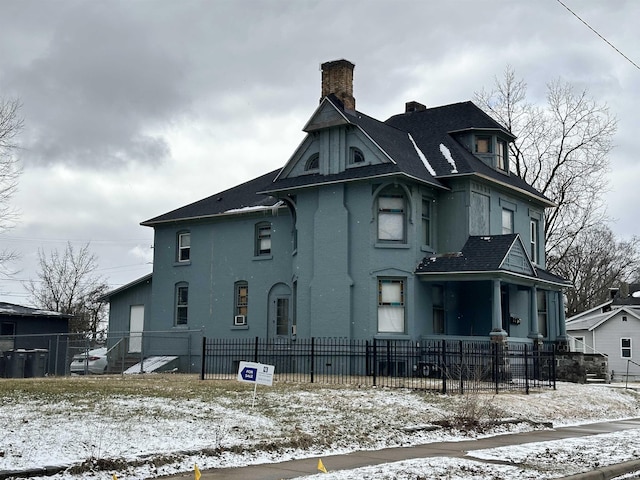 529 W Marion St, Elkhart, IN 46516 - snow covered property with a chimney, a fenced front yard, and a shingled roof