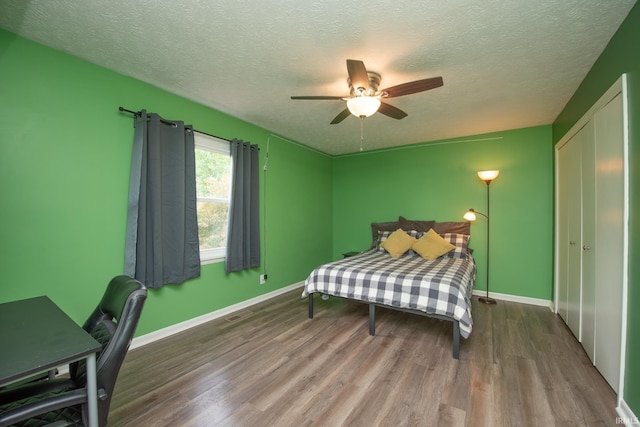 bedroom with wood finished floors, a textured ceiling, baseboards, and a ceiling fan