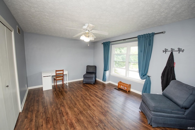 living area with wood finished floors, ceiling fan, baseboards, and a textured ceiling
