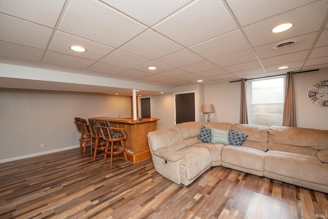 living room with a dry bar, wood finished floors, recessed lighting, baseboards, and a drop ceiling