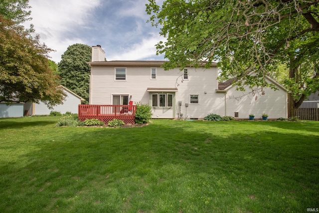 rear view of property featuring a deck, a chimney, and a lawn