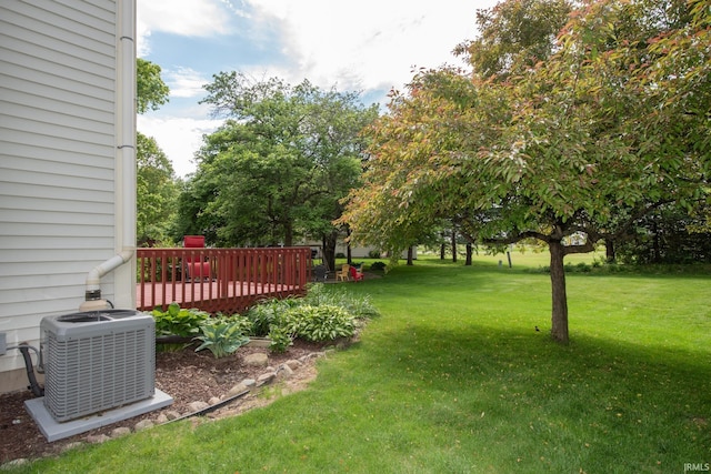 view of grassy yard with central AC and a deck