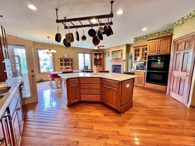 5936 County Road 427, Auburn, IN 46706 - kitchen featuring a textured ceiling, light wood-type flooring, light countertops, brown cabinetry, and glass insert cabinets