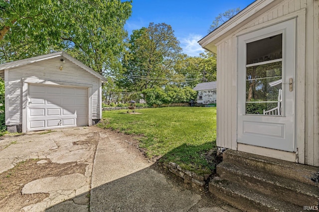 view of grassy yard featuring entry steps, an outbuilding, driveway, and a garage