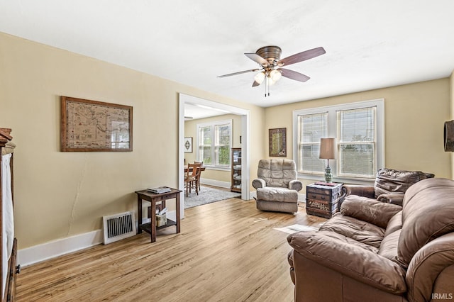 living room with baseboards, light wood finished floors, and a ceiling fan