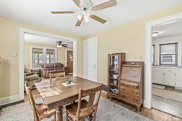 dining area with wood finished floors, ceiling fan, and baseboards