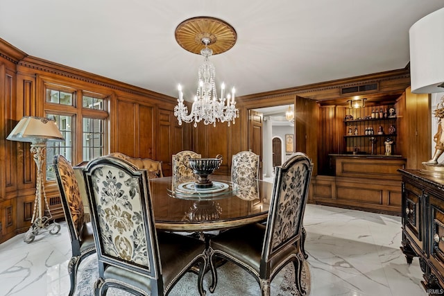 dining room with a chandelier, light marble finish flooring, and wooden walls