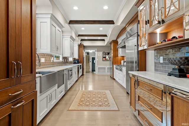 kitchen with crown molding, a sink, decorative backsplash, recessed lighting, and light stone countertops