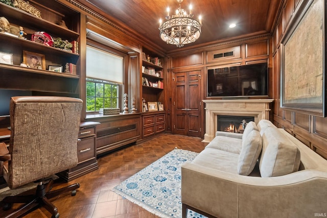 office area with a warm lit fireplace, built in features, a chandelier, recessed lighting, and crown molding