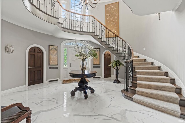 foyer featuring marble tiled floors, stairway, a chandelier, baseboards, and a high ceiling